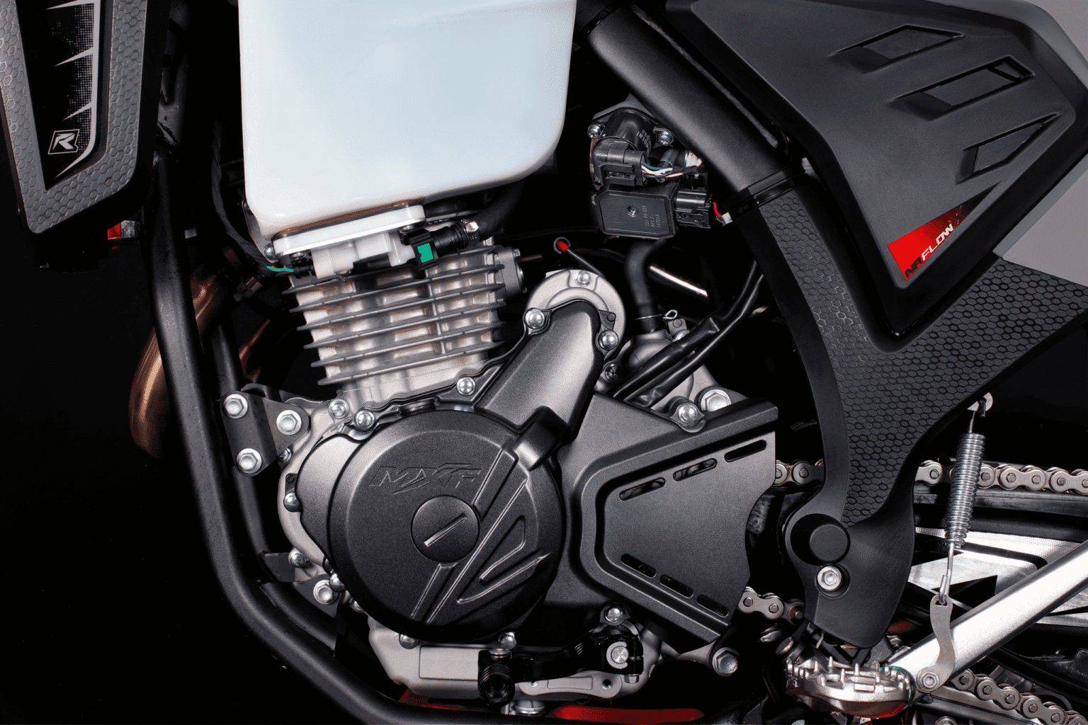 Lado esquerdo do motor da MXF 270 FI, mostrando a tampa do estator com logo MXF, pedal de câmbio e corrente.