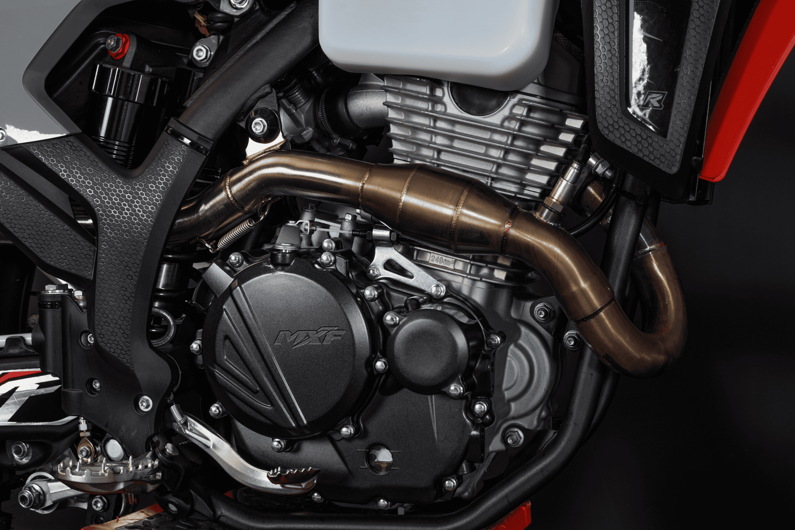 Close do motor da MXF 270 FI com escapamento em inox e texto Motor de Alta Performance ao lado.