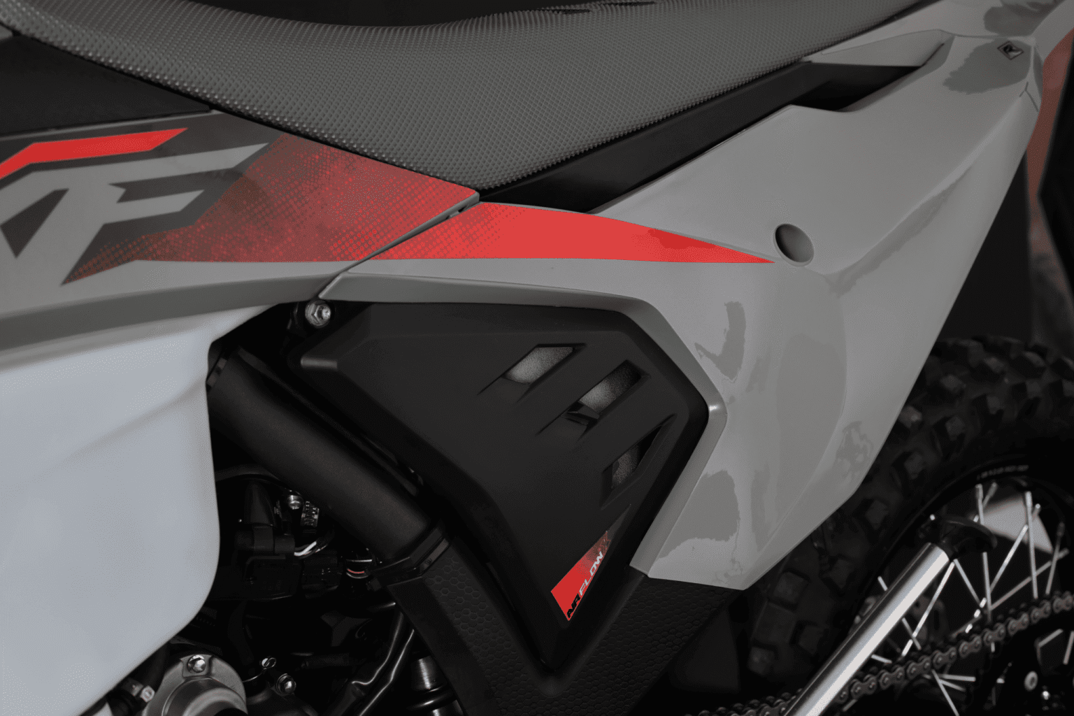 Lateral traseira da MXF 270 FI mostrando a caixa de filtro de ar preta com a etiqueta Airflow e carenagens cinzas.