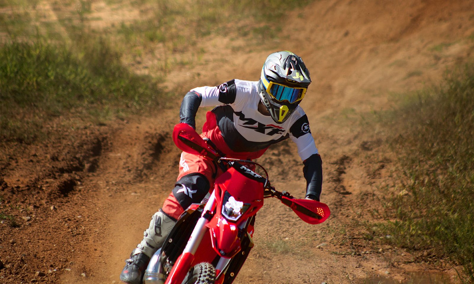 Close no piloto na MXF 250 TSX em curva fechada, mostrando o farol e a alta concentração.