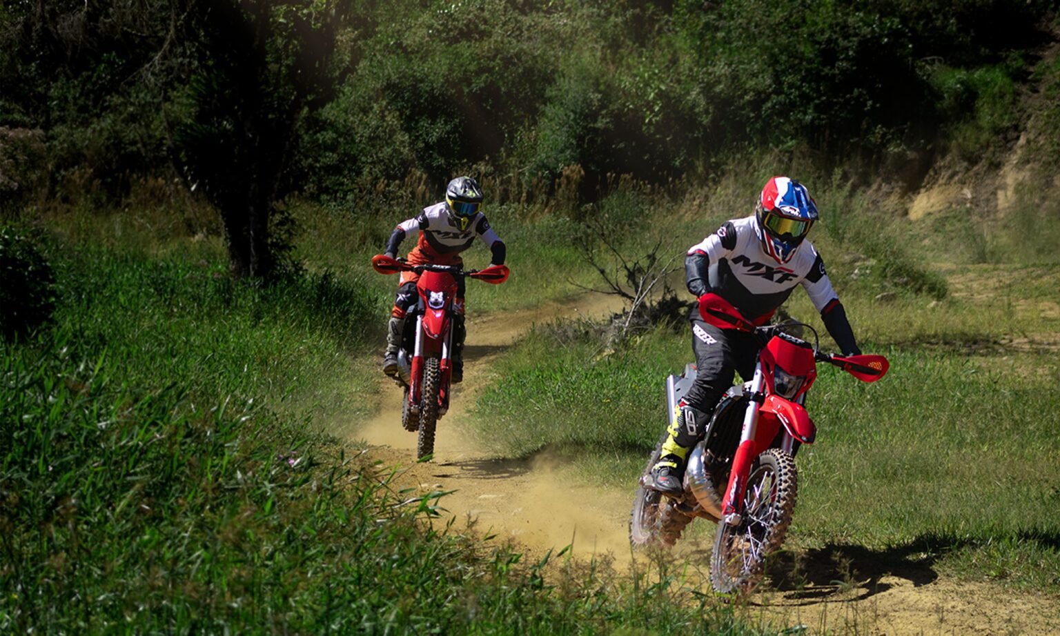 Piloto na MXF 300 TSX subindo um terreno rústico com foco no trabalho da suspensão.