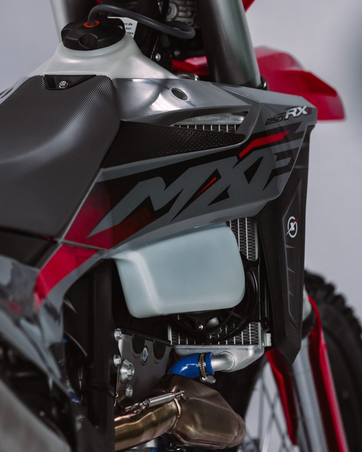 Detalhe da carenagem lateral da MXF 250 RXi, radiador e reservatório de líquido de arrefecimento.