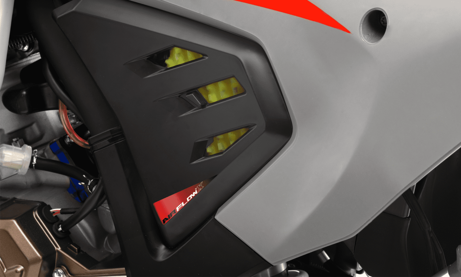 Painel lateral da MXF 250 TSX com entradas de ar, etiqueta "Airflow" e carenagem cinza