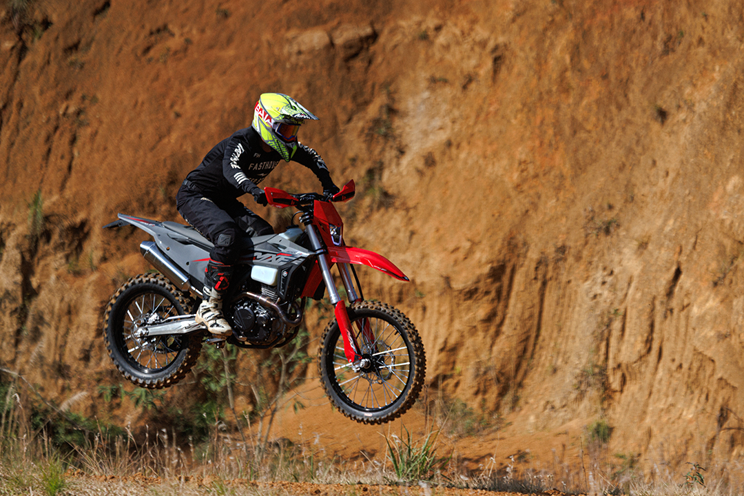 Piloto de motocross saltando alto com a moto MXF 270 FI em pista de terra vermelha.