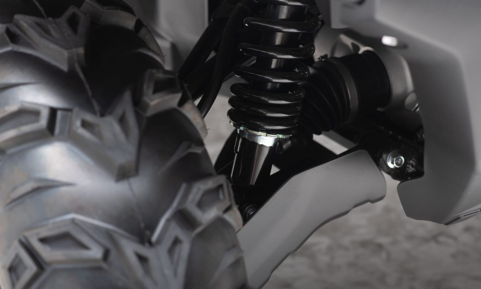 Detalhe técnico da suspensão independente Arched Rocker Arm do quadriciclo MXF Wolf 700L, mostrando os braços curvos que aumentam o vão livre do solo na MXF Burt Motos.