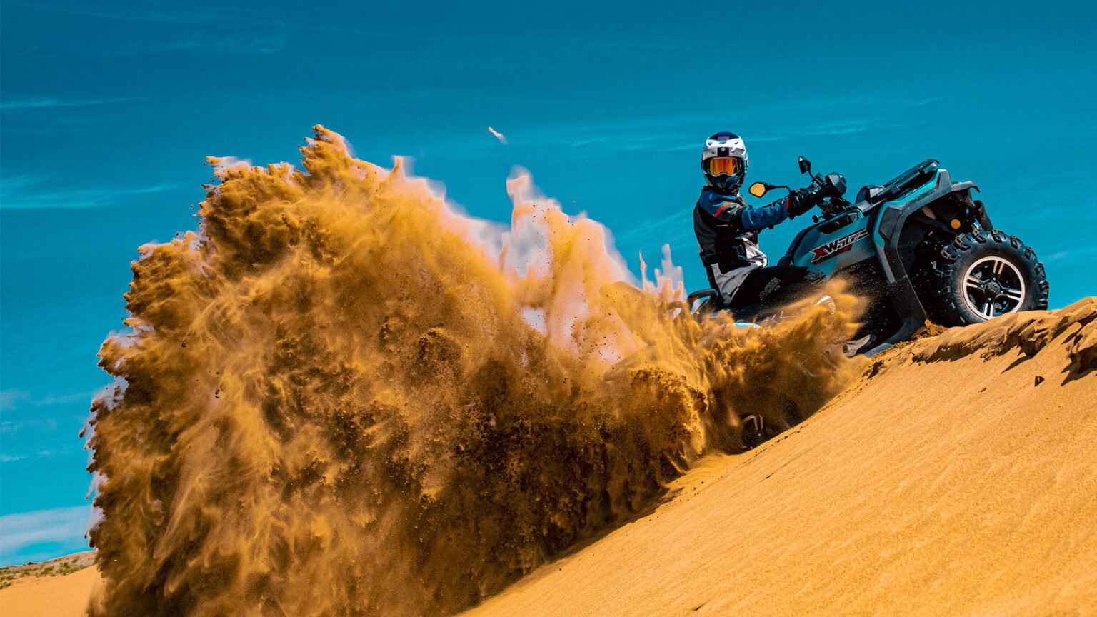Quadriciclo MXF Wolf 700L 4x4 acelerando em uma duna de areia e levantando uma nuvem de poeira, destacando a tração e a força do motor de 686cc na Burt Motos em Campinas.
