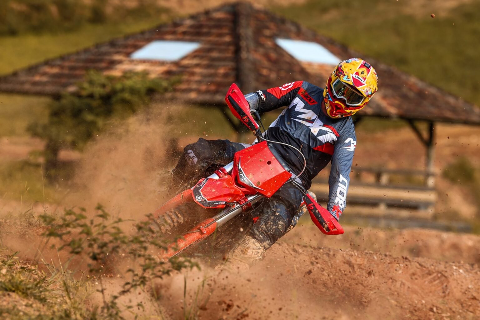 Piloto de motocross fazendo curva fechada na terra seca com a MXF 270 MXi vermelha, aproveitando o torque de 2,7 kgfm. Venha conhecer na Burt Motos em Campinas, São Paulo.