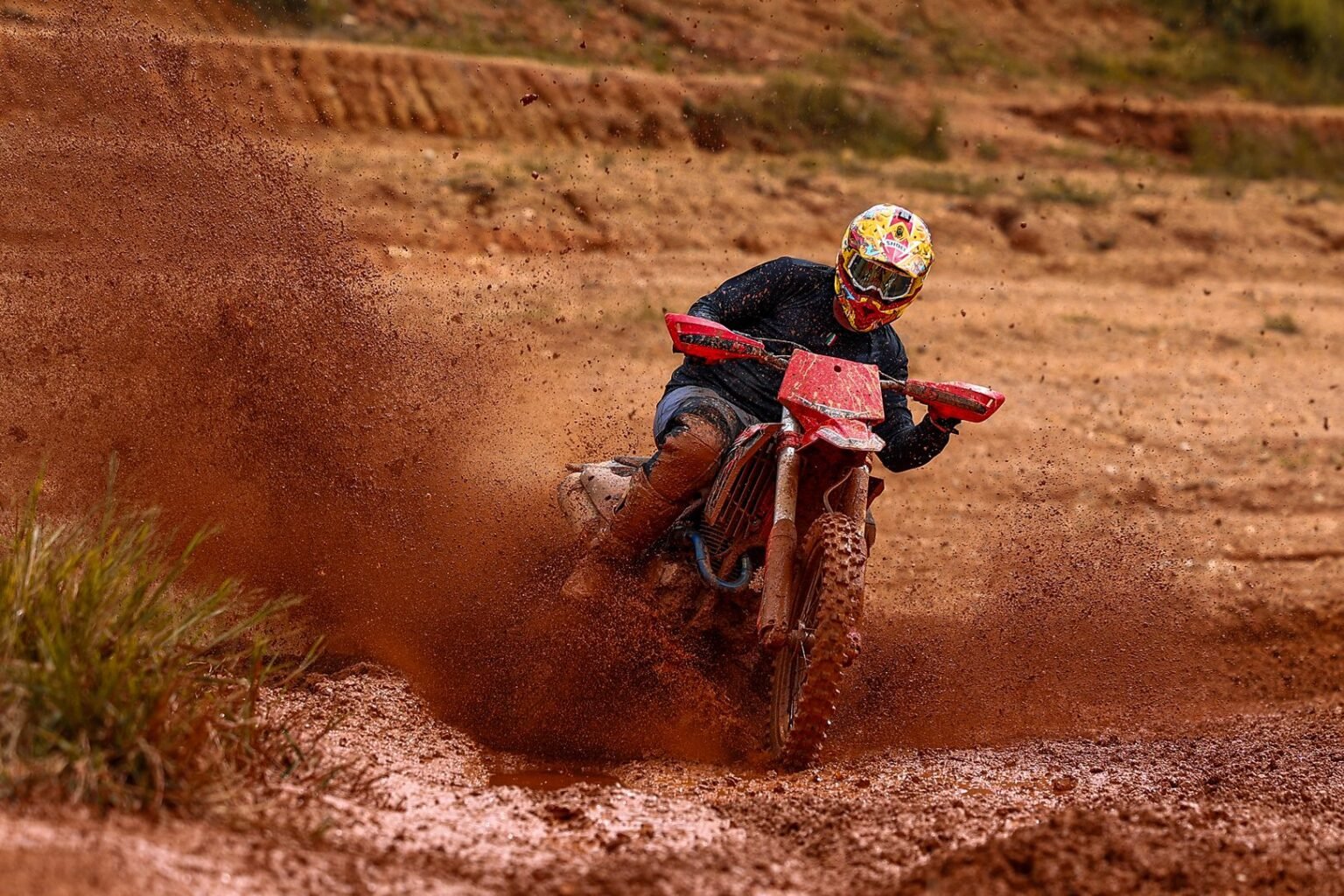 Piloto acelerando a MXF 270 MXi em uma curva com lama, levantando rastro de terra com o pneu traseiro Kenda. Potência de 28 cv em ação. Burt Motos, Campinas-SP.